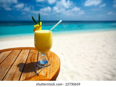 Bocal of fruity cocktail on a beach table