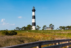 Bodie Island Lighthouse And Surrounding Buildings On The Outer Banks Of North Carolina Near Nags Head, With Wooden Fencing In The Foreground.