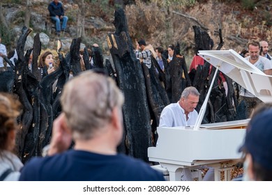 Bodrum, Cokertme, Turkey, 10212021; Pianist, Kerem Gorsev playing live open air on white piano. Jazz concert at "The Bodrum Cup" Sailing festival for awareness of forest fires in front of audience. 