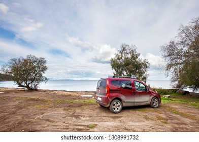 Bodrum, Turkey - January, 2019: Red transporter car parked on a muddy soil ground near the seashore on a cloudy day in cukurbuk bay of Gumusluk, Turkey