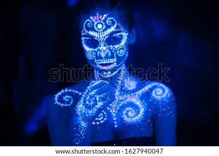 Body art on the body and hand of a girl glowing in the ultraviolet light. Body art glowing in ultraviolet light