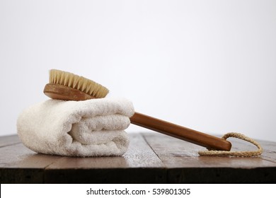 Body Brush With White Towel On The Wooden Table 