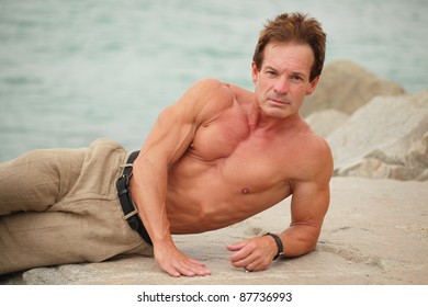 Body builder posing on the rocks