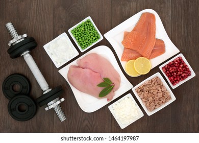 Body Building Health Food And Dumbbell Weights With High Protein Lean Chicken, Fish, Dairy, Vegetables And Fruit. Top View On Oak Wood.