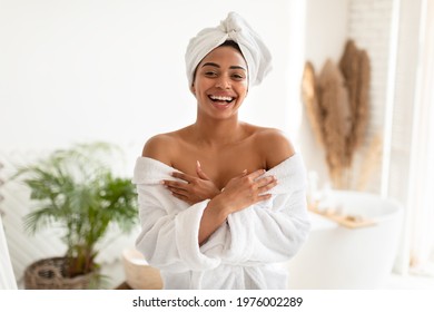 Body Care. Joyful African American Woman Posing Wearing White Bathrobe Standing After Shower In Modern Bathroom At Home, Smiling To Camera. Wellness, Spa And Bodycare Concept