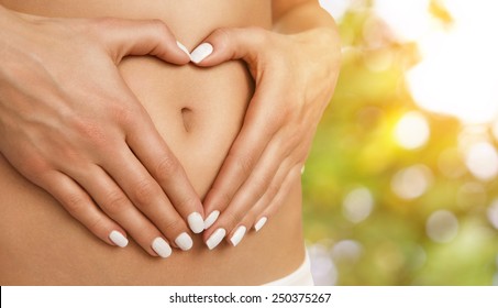 Body care, pregnancy diet concept, female hands forming heart shape on the stomach - Shutterstock ID 250375267