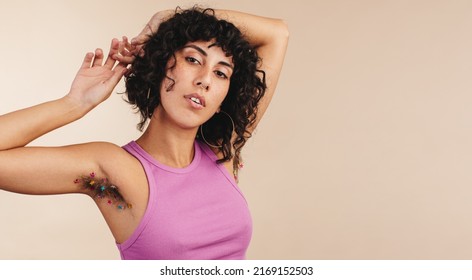 Body Confident Young Woman Looking At The Camera While Showing Her Confetti-decorated Underarms. Young Woman Making The Choice Not To Shave. Body Positive Young Woman Embracing Her Natural Body Hair.