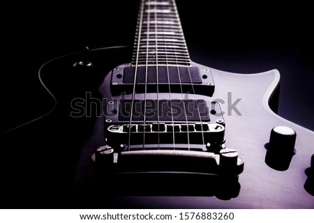 Body of a electric guitar in perspective with black background and purple hue