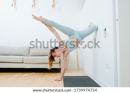 Body flexibility is a beautiful pose. The girl in good training arranged a home workout on acrobatics, leaning on the wall with her foot and standing on one hand