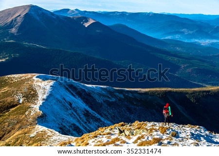 Body of Hiker bright sporty Clothing staying over Mountain Precipice foggy Peaks stacked on distant background covered Snow and Forest