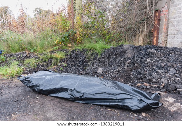 A body\
inside a body bag at an isolated\
location.