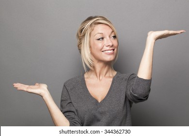 Body Language Concept - Sexy 20s Blond Woman Weighting Something On Both Palms Of Her Hands For Up And Down Value Of Product,studio Shot On Gray Background