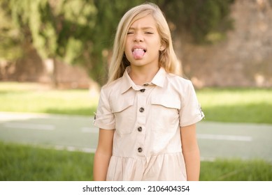 Body Language. Disgusted Stressed Out Beautiful Caucasian Little Kid Girl Wearing Dress Standing Outdoors, Frowning Face, Demonstrating Aversion To Something.