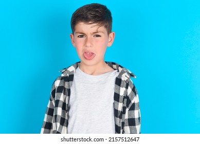 Body Language. Disgusted Stressed Out Caucasian Kid Boy Wearing Plaid Shirt Over Blue Background, Frowning Face, Demonstrating Aversion To Something.