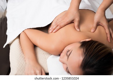 Body Massage on naked back of Mix Race Caucasian Asian woman by pressing fingers on pain or stress muscle point to release relax.  Therapist Spa body massage woman hands treatment on customer