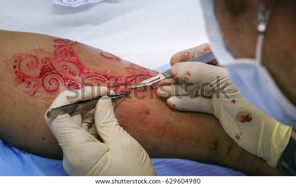 Body modification artist cut skin and flesh.\
Close-up view.