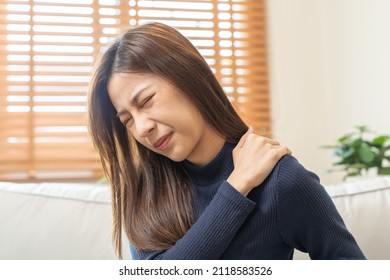Body Muscles Stiff Problem, Asian Young Attractive Woman, Girl Pain With Back Pain Ache From Work, Holding Massaging Rubbing Shoulder Hurt Or Sore, Painful Sitting On Sofa At Home. Healthcare People.
