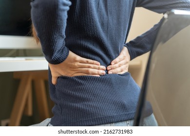 Body muscles stiff problem, asian young attractive woman, girl pain with back pain ache from computer work, holding massaging rubbing, hurt or sore while sitting on chair at home. Healthcare people. - Shutterstock ID 2162731983