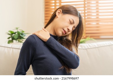 Body Muscles Stiff Problem, Asian Young Attractive Woman, Girl Pain With Back Pain Ache From Work, Holding Massaging Rubbing Shoulder Hurt Or Sore, Painful Sitting On Sofa At Home. Healthcare People.