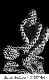 The body of nude woman  with black and white pattern and its reflection.  Black-and-white photo created with the projector