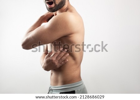 body pain. lats muscle injury. Portrait of a young muscular guy touching his thoracic cage in pain with painful grimace expression against white background.