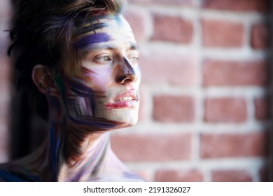 Body Painting, Art. Portrait Of A Handsome Manly Young Man Covered With Paints Posing On The Background Of A Brick Wall. Art And Male Beauty.