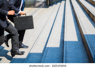 Body part business man.they are wearing black suit and carry a briefcase.They are running/walking  on staircase. Life a hurry and Business competition.Photo concept  business and succeed. - Shutterstock ID 1025193454