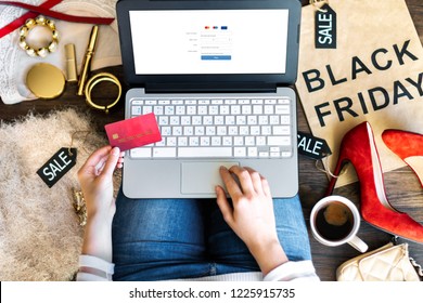 Body part of woman female adult with red high heels buying making payment on fashion cloth internet online store shop by typing credit debit card details with laptop during black friday holiday.