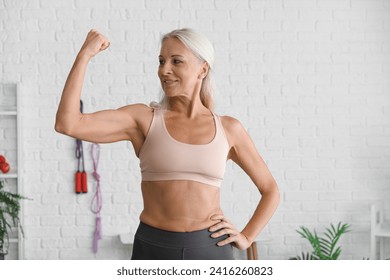 Body positive mature woman showing muscles in gym - Powered by Shutterstock