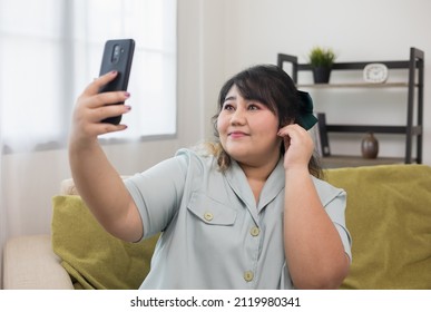 Body Positive Plus Size Female Holding Mobile Phone Taking Selfie Photo Using Smartphone Camera. Happy Woman Plus Size Video Call In Living Room.