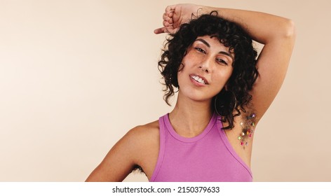 Body Positive Young Woman Looking At The Camera While Flaunting Her Confetti-decorated Underarm Hair. Happy Young Woman Making The Choice Not To Shave.Confident Young Woman Embracing Her Natural Body.