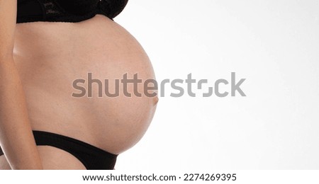 Body of a pregnant woman in black underwear on a white background. Fetal period, hormonal changes in a pregnant girl.