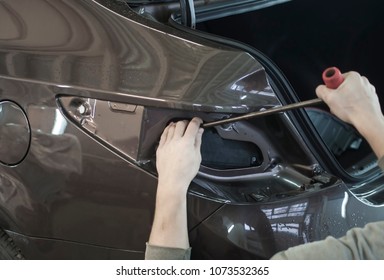 Body Repair. The Mechanic At The Auto Shop With Tools To Repair Dents In Car Body