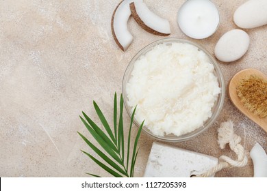 Body scrub of coconut oil, sugar and shavings in glass jar on stone table top view. Homemade cosmetic for peeling and spa care. Flat lay.