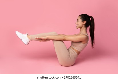 Body Shaping Workout. Smiling Sporty Young Woman In Sportswear Doing Abs Exercise With Leg Raise Isolated Over Pink Studio Background. Full Length, Banner. Sport And Fitness Concept