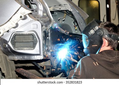 Body shop worker welding car panel.