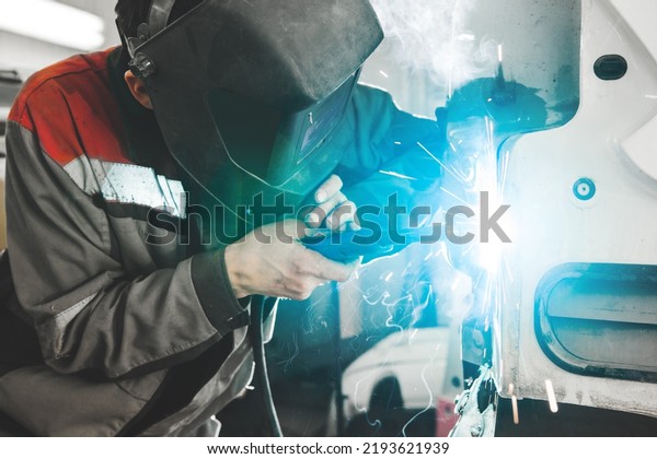 Body shop worker welding car body. Work with carbon\
dioxide weld.