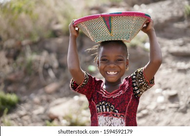 Body Shot Of Cute African Young Girl Carrying Food Basket And Blurred Background