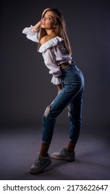 Body Shot Of A Stylish Woman Posing In Trendy Ripped Jeans And White Tank Top