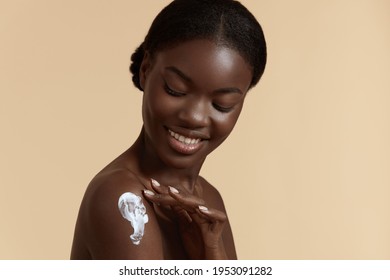 Body Skin Care. Smiling Black Woman Applying Body Cream. Beautiful African American Girl With Cosmetic Moisturizing Lotion On Soft Skin On Shoulder 