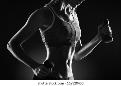 Body of slim female in activewear doing exercise with dumbbells