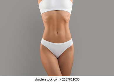 Body Slimming Concept. Unrecognizable Female With Slim Sporty Figure In White Underwear, Cropped Shot Of Woman Torso With Flat Abdomen Isolated Over Grey Studio Background, Copy Space