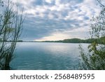 A body of water with a cloudy sky in the background. The water is calm and still. The sky is overcast, giving the scene a somewhat somber mood