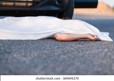 Body Of A Young Child Covered By A Sheet Lying On The Street In Front Of The Bumper Of The Car That Ran Him Over With Foreground Copy Space