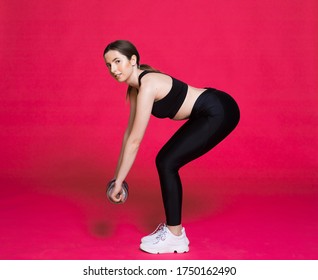 Body Of A Young Fit Woman Lifting Dumbell. Shot In Studio On A Red Background.