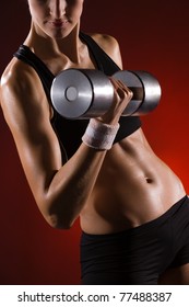 Body Of A Young Fit Woman Lifting Dumbell. Shot In Studio On A Red Background.