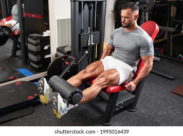 Bodybuilder doing leg extensions at the machine in the gym - Powered by Shutterstock