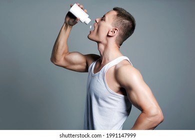 Bodybuilder Eating Pills, Steroids. Handsome Fitness Boy With Bottle. Sport Body Muscular Man. Sports Nutrition