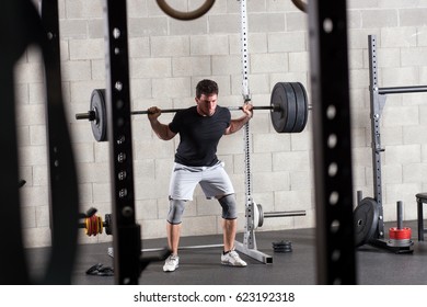 Bodybuilder Exercising On Squat Rack In Gym, Weight Equipment In Foreground