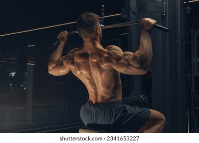 Bodybuilder in gym. Muscular man working out in gym, doing exercise back lat pulldown. Strong male rear view. - Powered by Shutterstock